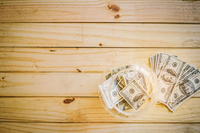 Directly above shot of paper currency in jar on wooden table