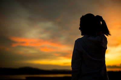 Side view of woman standing against sky during sunset