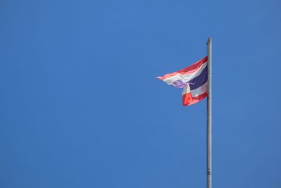 Low angle view of flags against clear blue sky