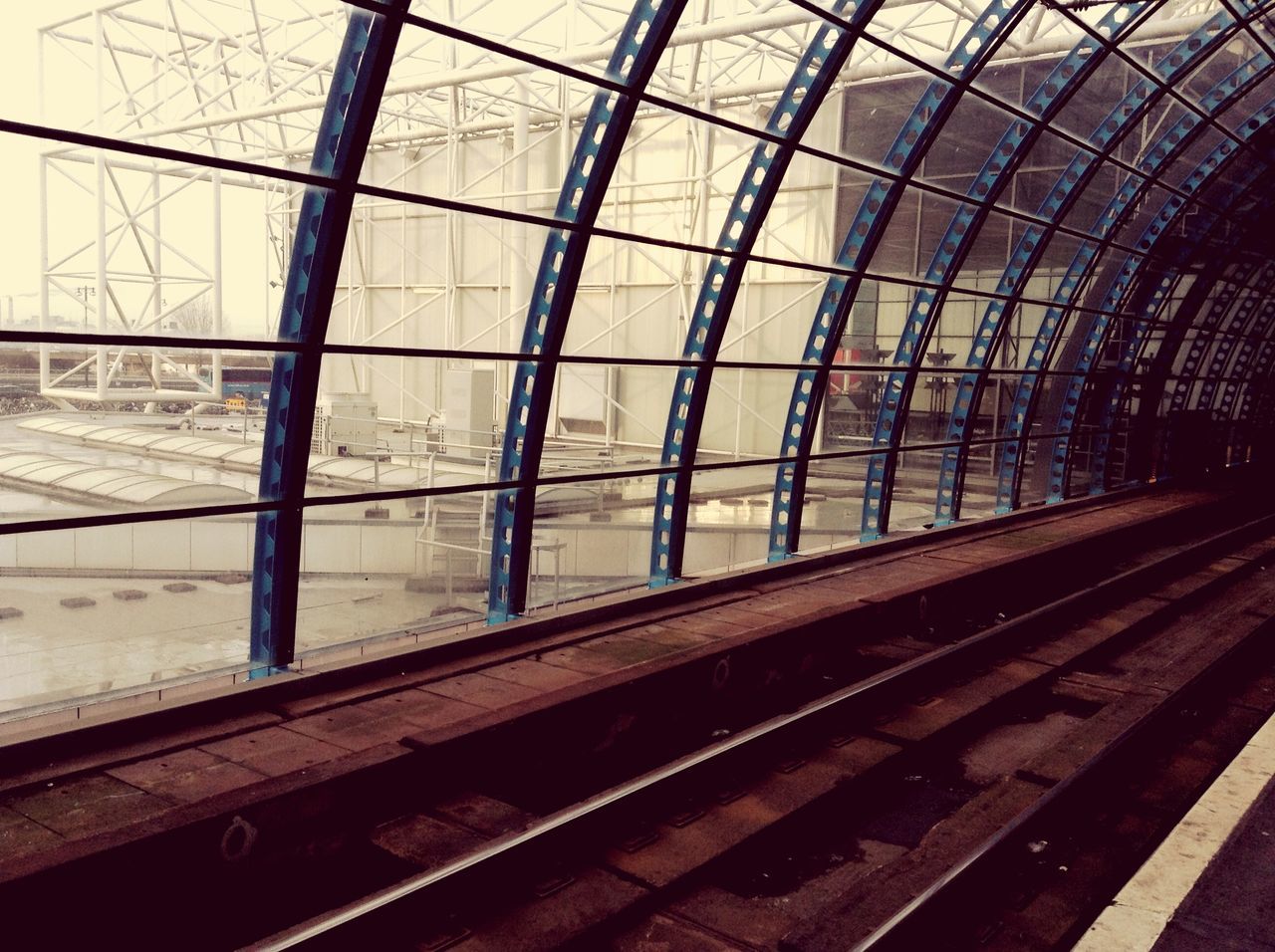 railroad track, rail transportation, transportation, indoors, railroad station, public transportation, railroad station platform, built structure, architecture, metal, train - vehicle, glass - material, train, transparent, railway track, day, travel, ceiling, passenger train, sky