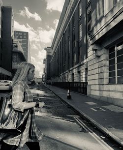 Side view of woman walking on street amidst buildings in city