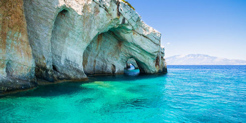 Rock formation in sea against blue sky