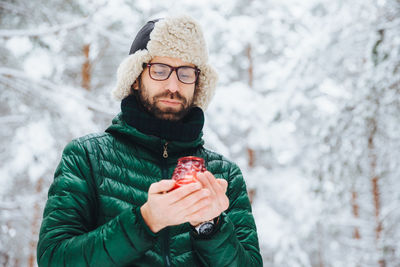 Portrait of young man holding ice cream cone during winter