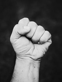 Close-up of hand holding leaf against black background