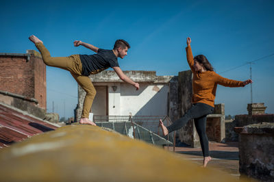 Low angle view of man jumping against clear sky