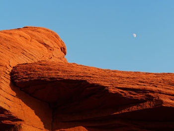 Low angle view of rock formation against clear blue sky