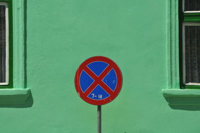 Close-up of road sign on green wall