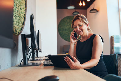 Businesswoman having business call working on tablet in office. mature busy woman using technology