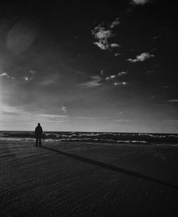 Silhouette of man standing on tree trunk