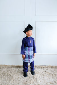 Full length of a boy standing against wall