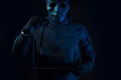 Portrait of young man standing against black background