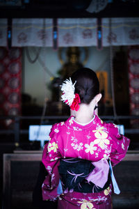 Rear view of woman standing by pink flower