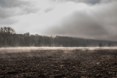 Scenic view of field against cloudy sky during foggy weather