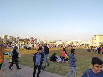 People walking in city against clear sky