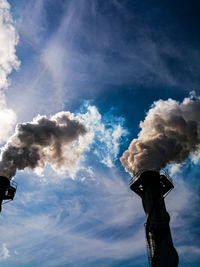 Low angle view of smoke stacks against sky