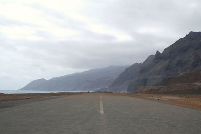 Road leading towards mountains against sky