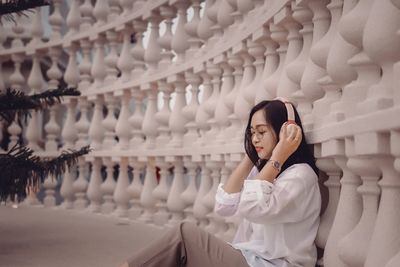 Portrait of young woman standing against wall