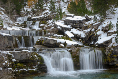 Scenic view of waterfall in forest during winter