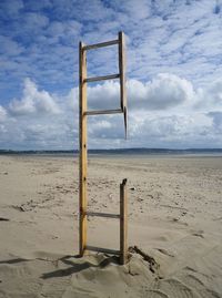 Close-up of broken ladder at beach against cloudy sky