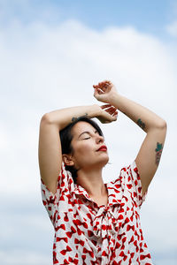 Low angle view of young woman standing against sky