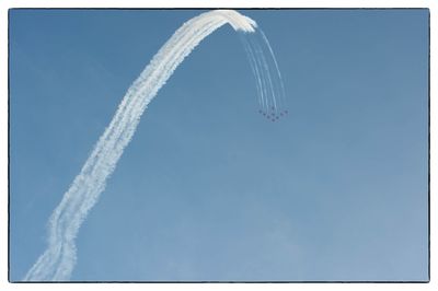 Low angle view of airplane flying against clear blue sky