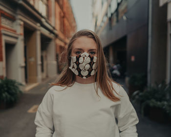 Portrait of young woman wearing mask standing outdoors