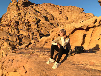 Full length of woman sitting on rock