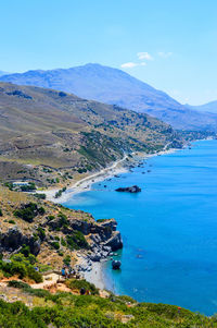 High angle view of sea and mountains against blue sky