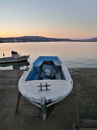 Boat moored on beach against sky during sunset