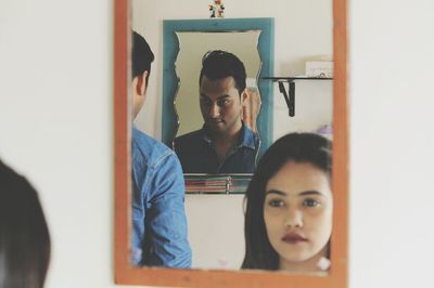 Close-up of young couple sitting against wall