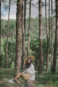 Woman holding tree trunk in forest