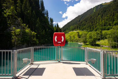 Life belt on fence with lake in background against tree mountains