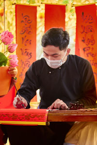 Man wearing mask writing on prayer flag