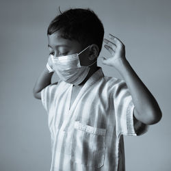 Portrait of boy standing against gray background