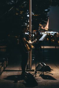 Man playing music in city at night