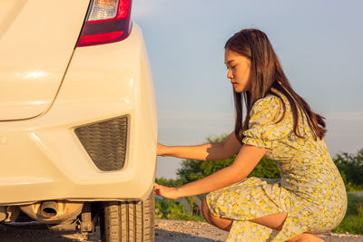 Side view of woman standing by car