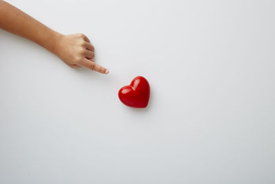 Close-up of hand holding heart shape over white background