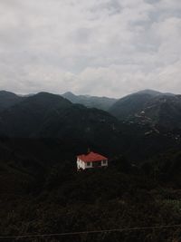 House on mountain against cloudy sky