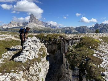 Man on rocks by mountains against sky