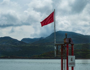 Flag by lake against sky