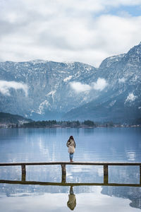 Woman standing on bridge over lake against mountains