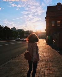 Rear view of woman walking on sidewalk in city