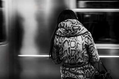Rear view of woman standing against train at station