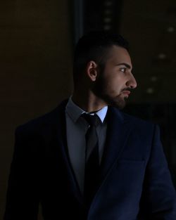 Portrait of businessman standing against black background
