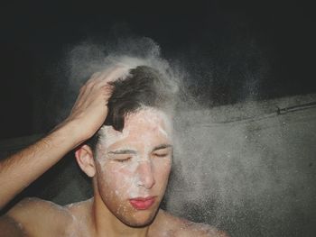 Shirtless man with white powder paints on face at night