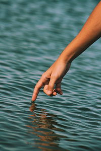 Cropped image of person touching water in river