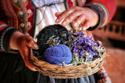 Close-up of woman holding flowers and wool in basket
