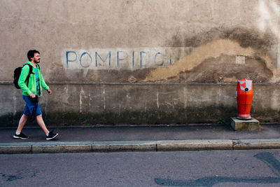 Full length of man standing by wall