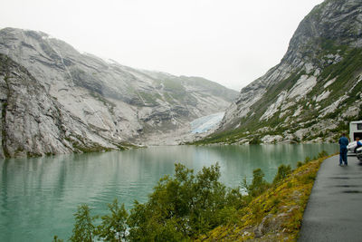 Rear view of lake amidst mountains against sky