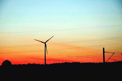 Silhouette wind turbine against sky during sunset